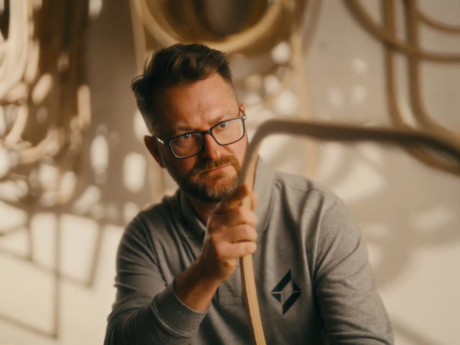Nowoczesna produkcja filmowa dla marek premium 1 Mężczyzna w okularach i szarej koszulce trzyma pędzę. Pracownia budowlana. Profesjonalny portret twórcy.