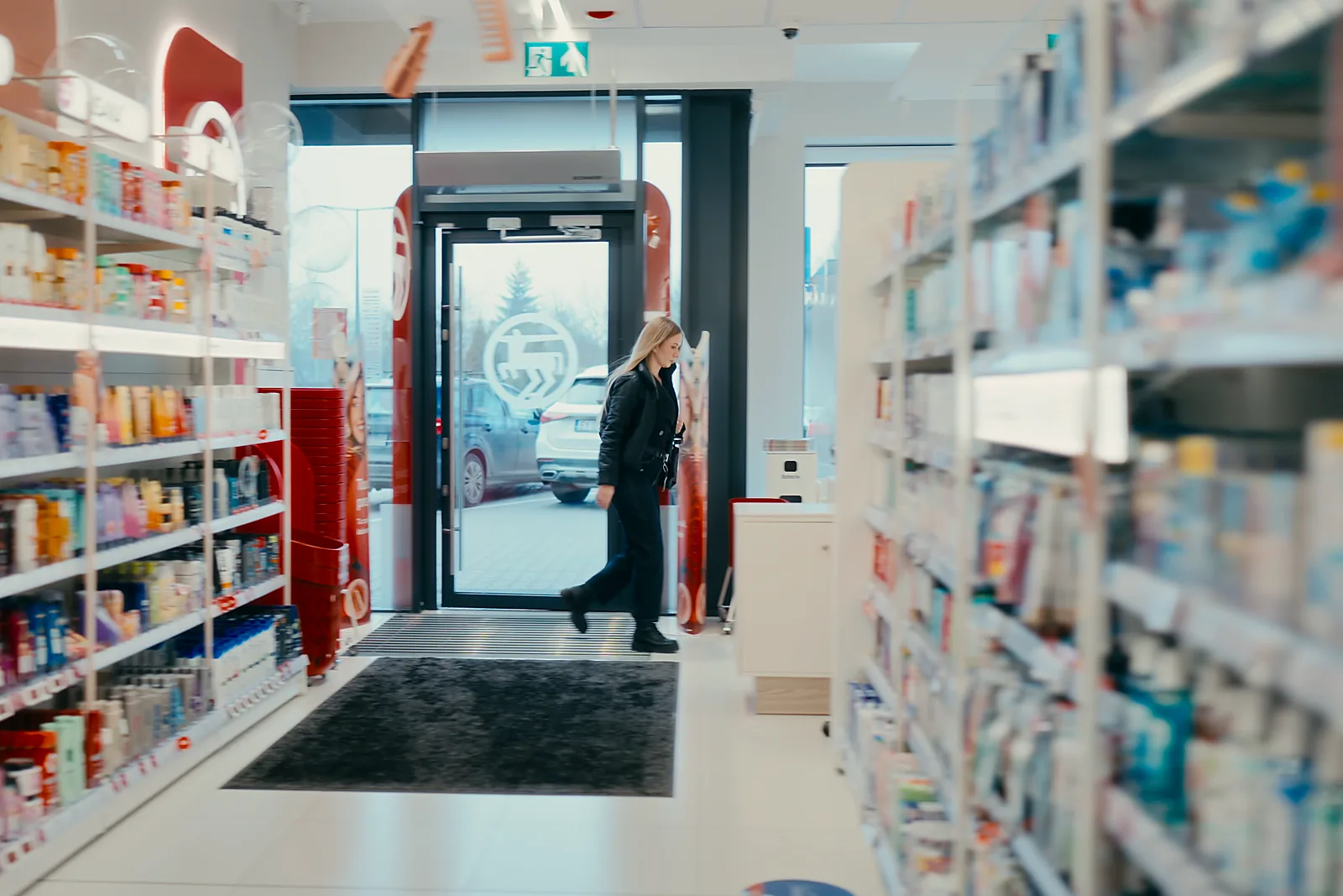 Filmy korporacyjne 4 Wnętrze drogerii Rossmann z klientką przy wejściu, kadr z filmu wewnętrznego.