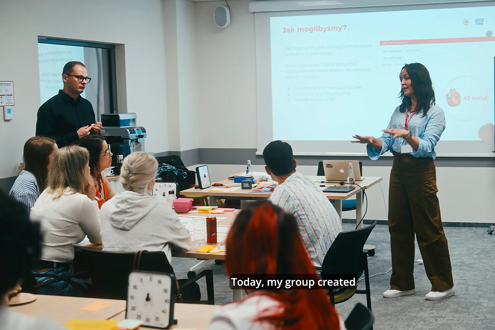 Filmy szkoleniowe 1 Prowadząca warsztat przed grupą w sali szkoleniowej, kadr z produkcji filmu szkoleniowego.