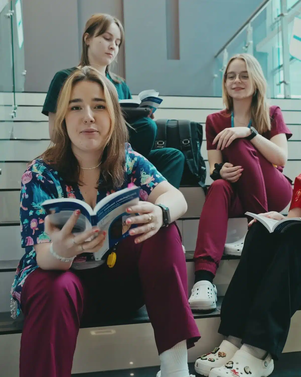 Filmy promocyjne dla uczelni - Uniwersytet Medyczny w Łodzi 1 Studentki Uniwersytetu Medycznego w Łodzi z podręcznikami na schodach kampusu, kadr z filmu rekrutacyjnego uczelni